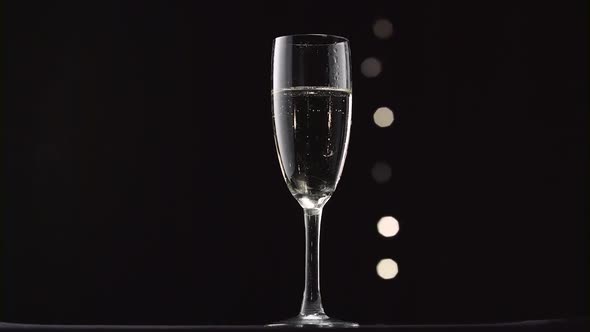 Chilled Glass of Champagne. Bokeh Blinking Black Background