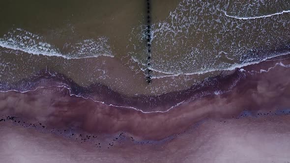 Beautiful aerial view of an old wooden pier at the Baltic sea coastline, overcast day, white sand be