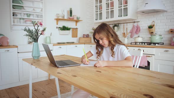 Cute Little Girl Sitting at Kitchen Table Using Laptop for Distance Learning Slow Motion