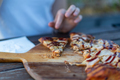 person eating a pizza with bbq sauce at an outdoor cafe - PhotoDune Item for Sale