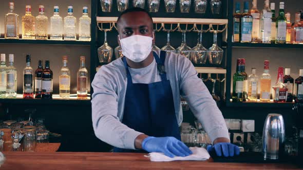 Male African Barista in a Face Mask is Wiping the Table
