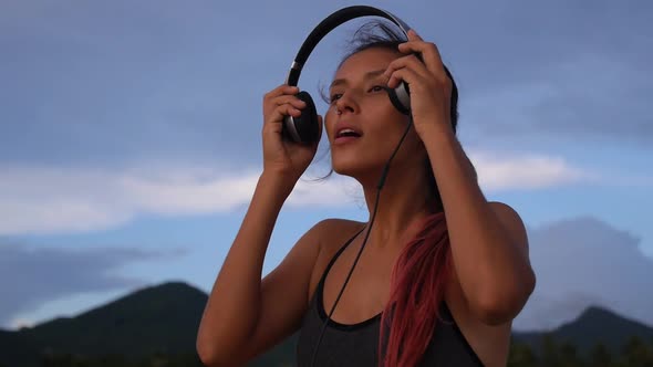 Young Multi-Ethnic Brunette Female Listening Music on Beach in Headphones