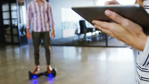 Man on hoverboard using digital tablet with colleagues