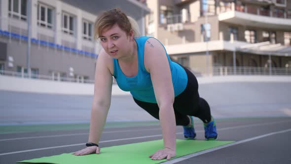 Overweight Woman Doing Push Ups on Sports Stadium