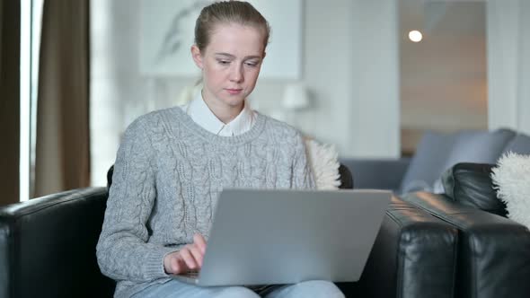 Serious Young Woman Working From Home on Laptop 