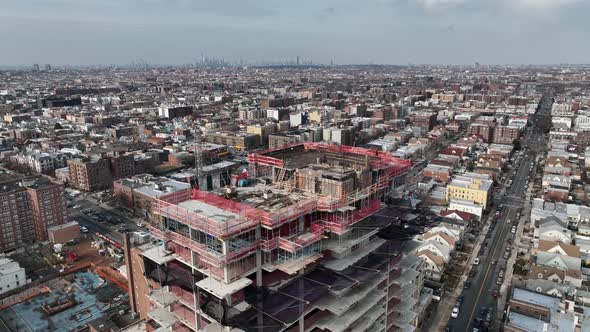 A high angle view above a new high-rise construction site in Brooklyn, NY. The drone camera boom up