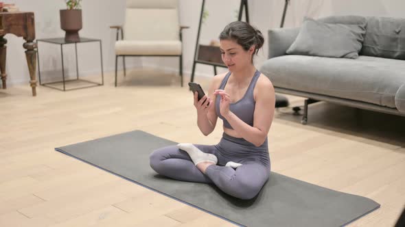 Young Indian Woman Using Smartphone on Yoga Mat at Home