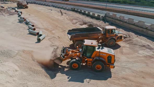 Aerial shot of a large loader loading a truck in a construction site