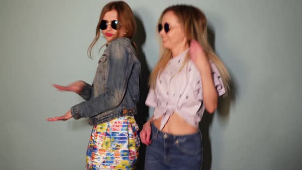 Two Carefree Young Girls Going Crazy. Women in hipster summer clothes having fun and dancing