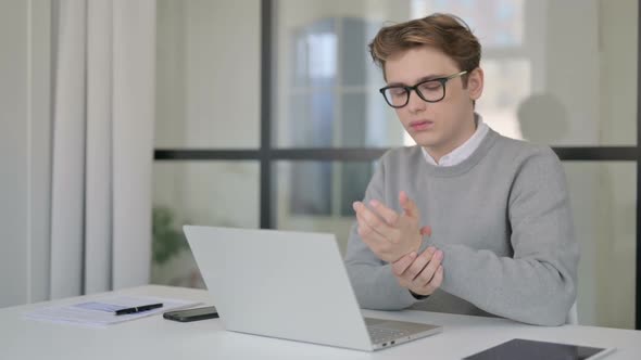 Young Man Having Write Pain While Working on Laptop in Modern Office
