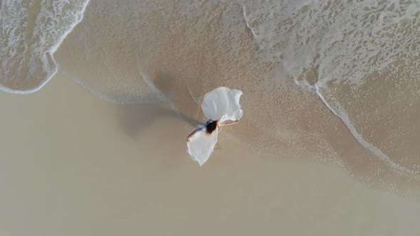 Top View of a Young Woman in White Dress Spinning on a Tropical Beach