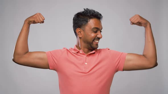 Indian Man Showing Biceps Over Grey Background