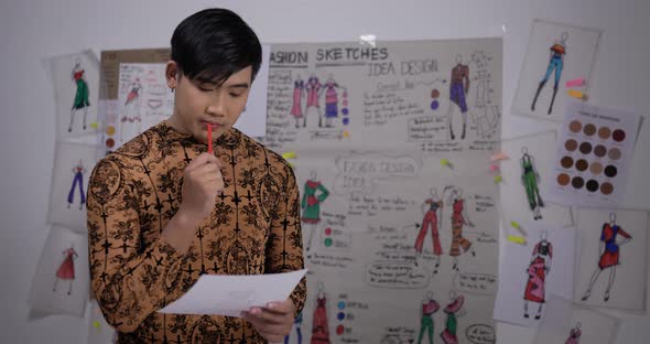 Asian clothing designer working in his office, creating a new clothes collection