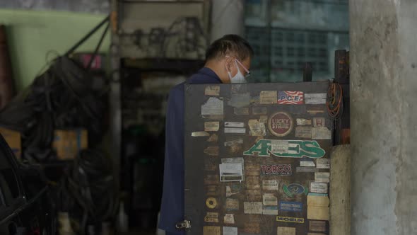 Male Mechanic Looking For Auto Spare Part Inside The Cabinet At The Workshop