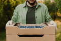 Farmer hands taking and holding cardboard box full of containers with blueberry - PhotoDune Item for Sale