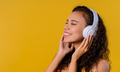 Positive woman listening music, enjoying with headphones on yellow studio - PhotoDune Item for Sale