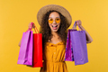 Excited woman with colorful paper bags after shopping yellow studio background - PhotoDune Item for Sale