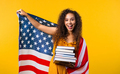 American woman student with stack of books on yellow background.Education in USA - PhotoDune Item for Sale