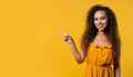 Smiling woman presenting something isolated on yellow background. copy space - PhotoDune Item for Sale