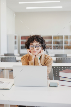 thoughtful woman works in library, watches an educational webinar on Internet, is bored. coworking