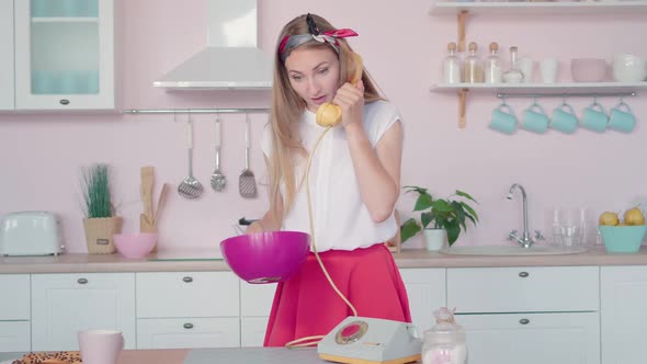 Portrait of 1960s Young Housewife Cooking and Talking on Retro Phone. Beautiful Woman Beating Eggs