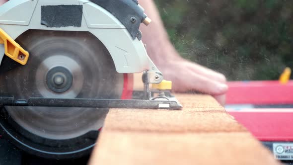 Close Up Slow Motion Shot of Electric Power Saw Slicing Through Plank of Wood Outside