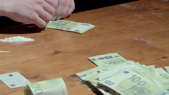Drug Addict Rolls 100 Euro Banknote On The Table And Snort Powdered Cocaine Drug. close up