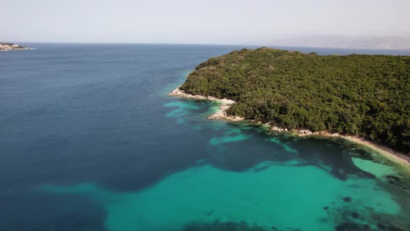 Flight above deserted, green coastal line in greece. Green mountains and blue water with white beach