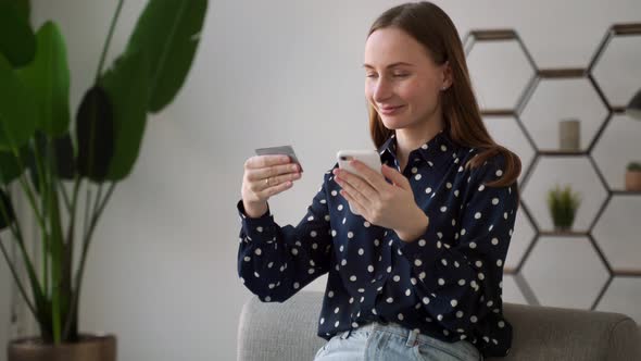 Beautiful Young Woman with a Cheerful Expression Holding a Smartphone and a Credit Card Shopping