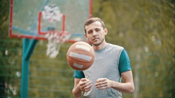 A Man Standing on a Sports Ground and Throws Up the Basketball Ball