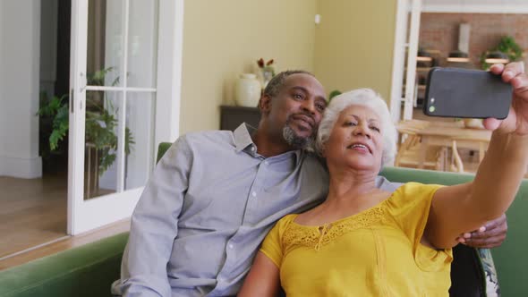 Senior African American husband and mixed race wife spending time and taking photo at home