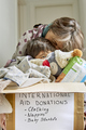 Grandmother kissing her grandchild supporting a box with humanitarian aid for a natural disaster  - PhotoDune Item for Sale