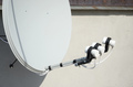 White satellite dish with three converters mounted on residental building rooftop - PhotoDune Item for Sale