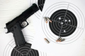 Gun and many bullets shooting targets on white table in shooting range polygon - PhotoDune Item for Sale