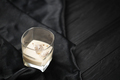 Glass of Irish cream baileys liqueur with ice cubes on dark fabric and wooden bar - PhotoDune Item for Sale