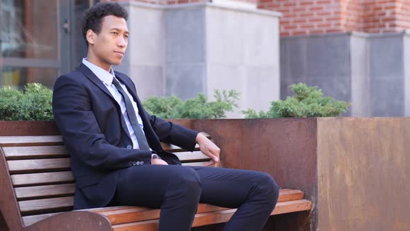 Pensive Serious African Businessman Sitting on Bench