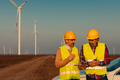 Two engineers standing in field with wind turbines - PhotoDune Item for Sale