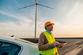 Smiling engineer standing by car on a wind farm - PhotoDune Item for Sale