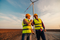Colleagues shaking hands with wind turbines on background - PhotoDune Item for Sale