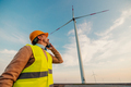 Man in uniform talking on mobile on farm with wind turbines - PhotoDune Item for Sale