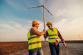 Colleagues shaking hands with wind turbines on background - PhotoDune Item for Sale
