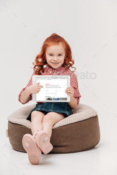 adorable little girl smiling at camera while holding digital tablet with airbnb website on screen