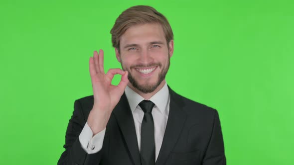 Young Businessman with Ok Sign on Green Background