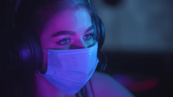 Young Woman in Headphones and White Protective Face Mask Playing a Game in Gaming Club