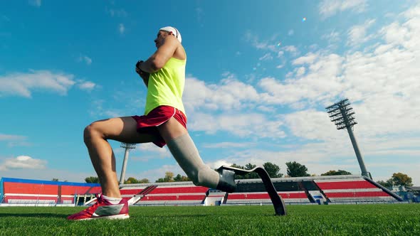 Male Athlete with a Prosthetic Leg Is Stretching