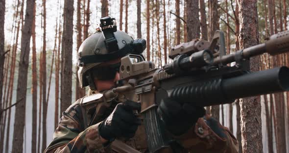 A Soldier in a Special Military Uniform with a Helmet on His Head and with a Sniper Rifle in the