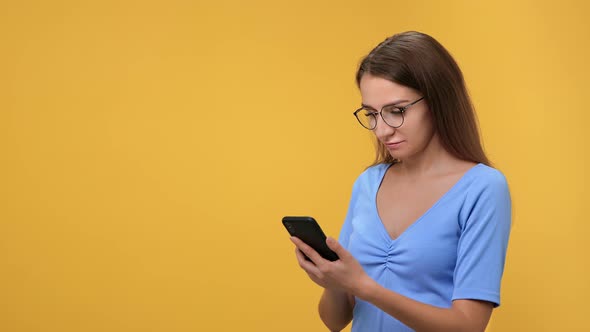 Cheerful Smiling Woman Chatting Typing Message Use Smartphone Isolated on Orange Studio