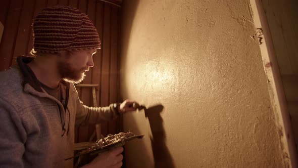 WIDE, BACKLIT, A handsome professional plasterer using a Japanese trowel