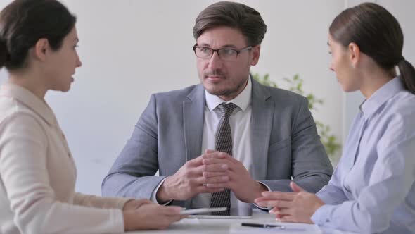 Middle Aged Businessman Talking to Female Colleagues in Office