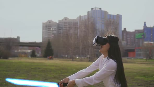 Modern Playing in Virtual Reality Glasses with Laser Lightsaber Swords Outdoors